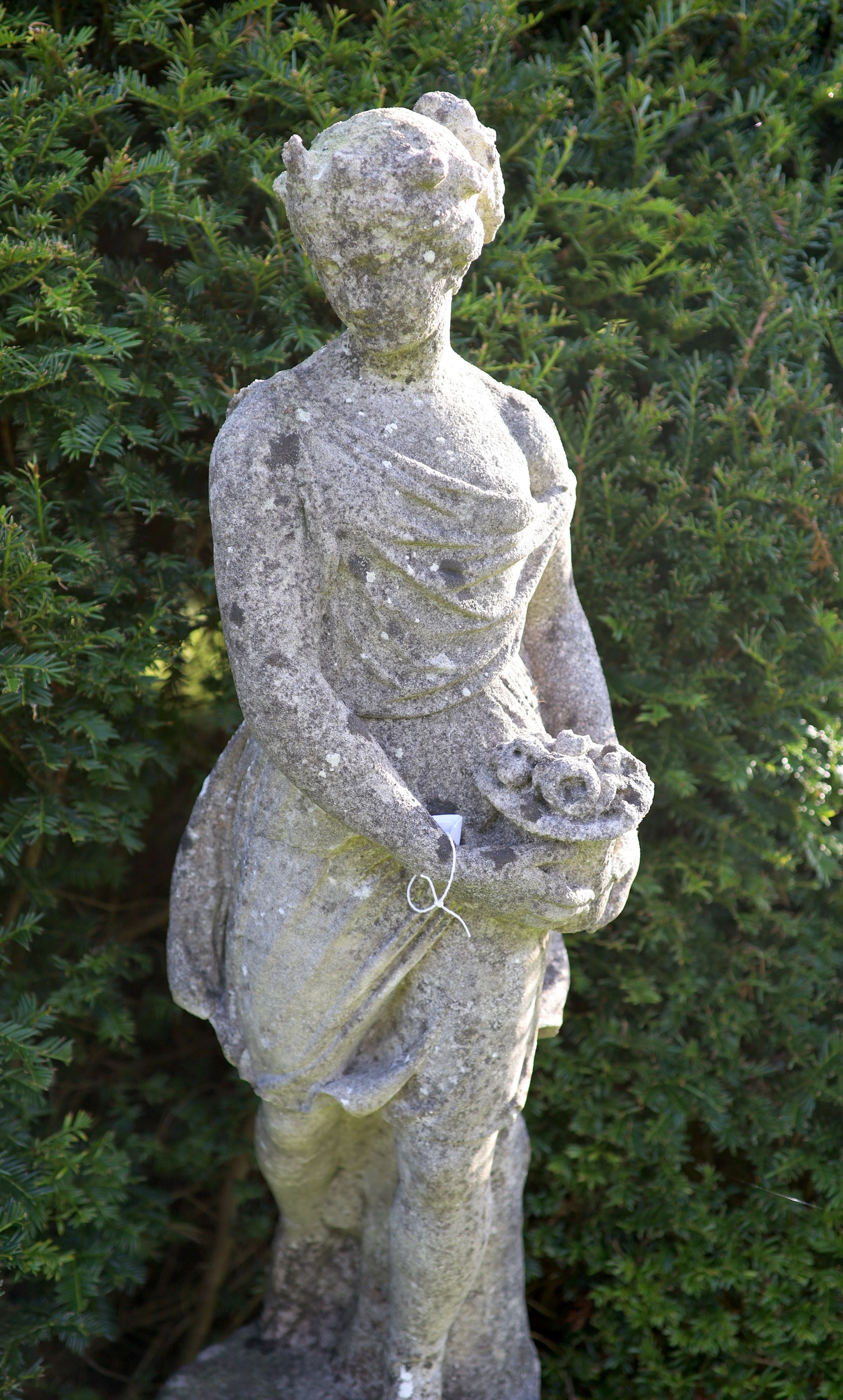 A reconstituted stone garden statue modelled as Flora, on turned socle, height overall 154cm